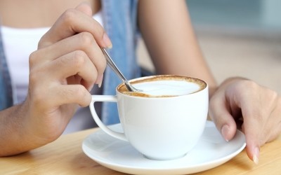 Woman stirring coffee in white cup-pong